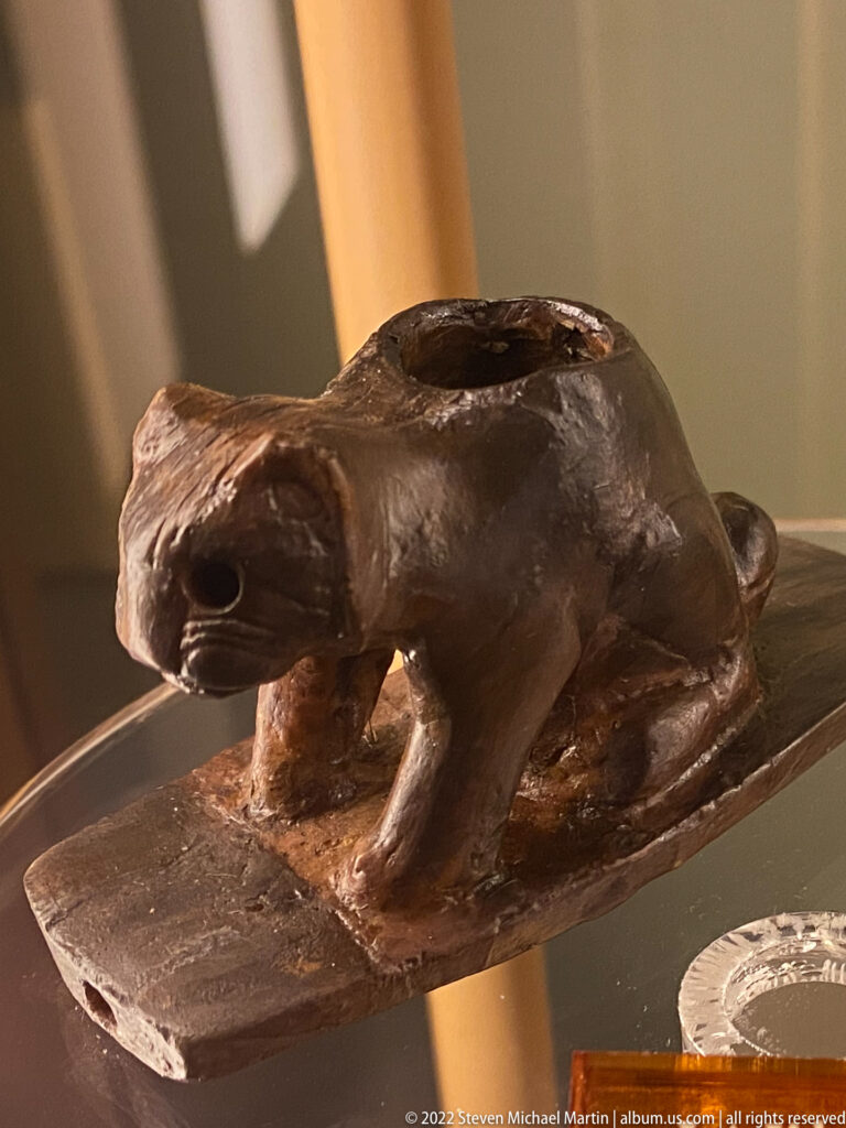 A brown animal-shaped stone object with a top opening rests on a flat base.