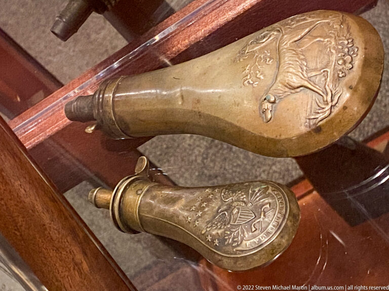 Embossed circular metal pieces and a ring-shaped fragment are arranged beside a label.
