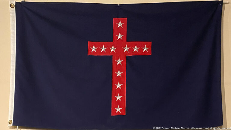 A dark blue flag displays a red, white-edged cross set with white stars.