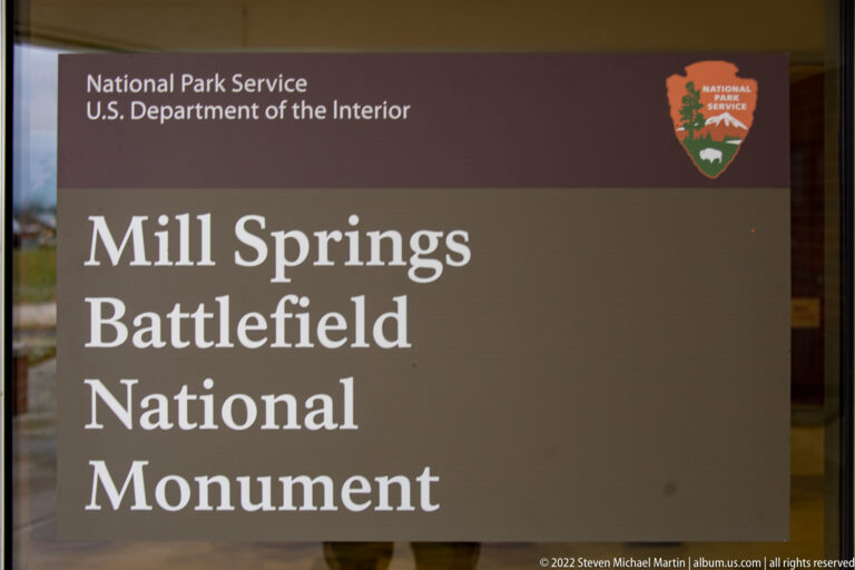 A brown sign reads Mill Springs Battlefield National Monument beside the NPS arrowhead.
