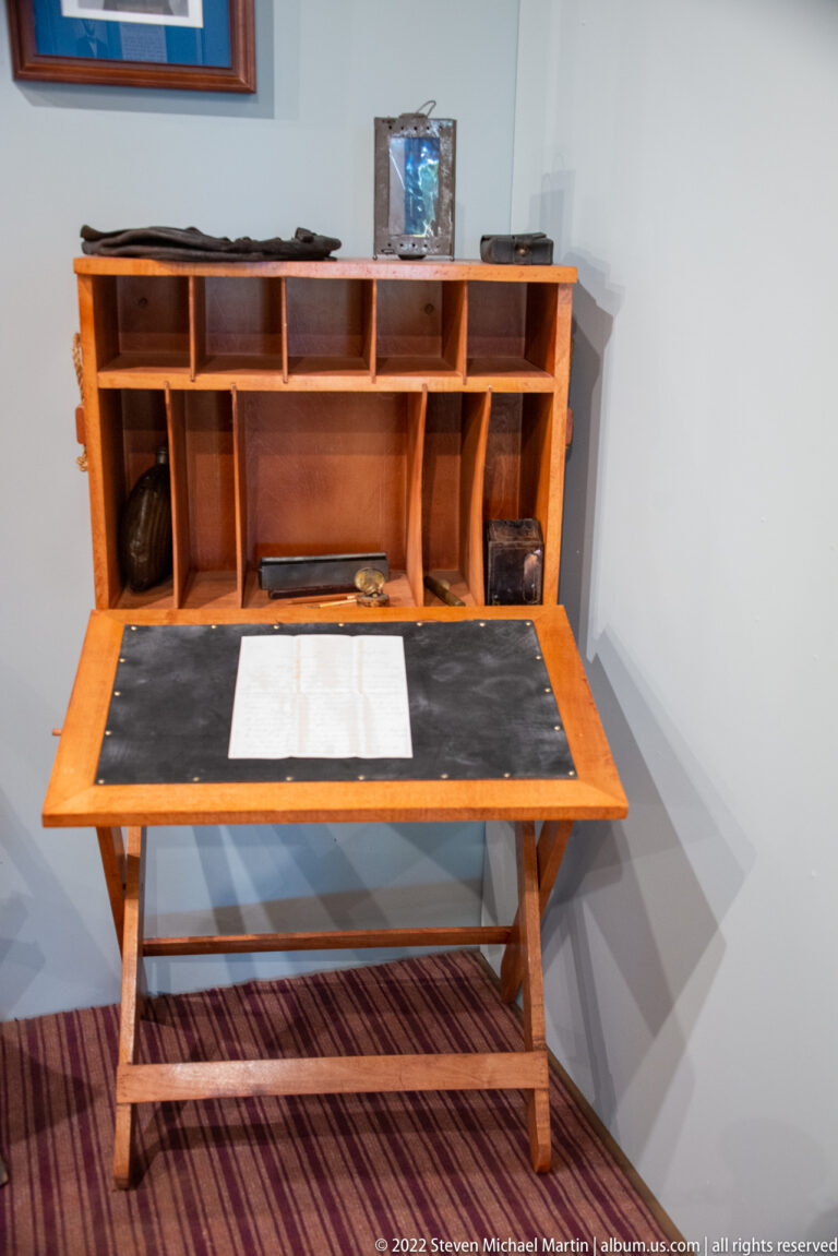 Open wooden writing desk with a sloped writing surface, small compartments and drawers.