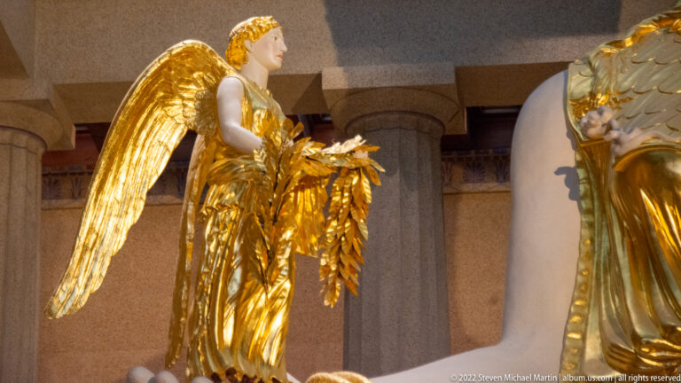 A small gilded winged figure stands in Athena’s hand beside a leafy ornament.