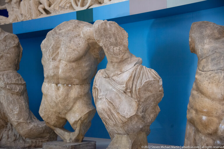 A muscular torso and a draped torso stand side by side against blue.