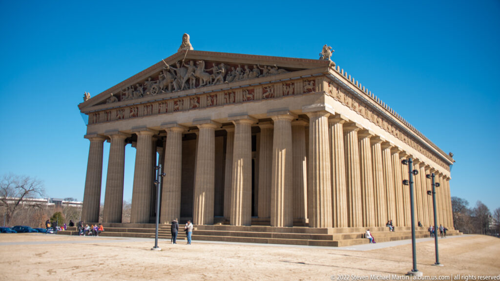 Visitors approach the Parthenon’s columned entrance as its long side recedes to the right.