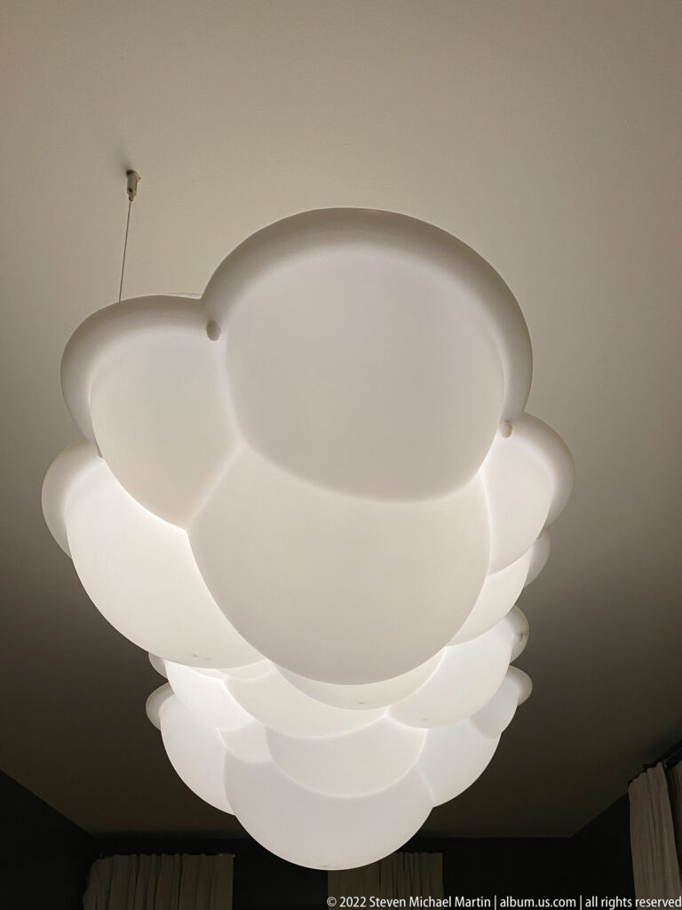 Overlapping white circular discs form a layered ceiling light against a plain ceiling.