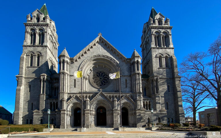 The cathedral’s stone facade has twin towers, a central rose window, and three arched entrance portals.