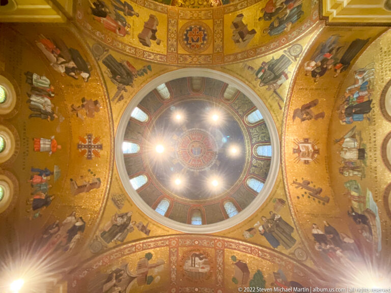 A circular mosaic dome contains a central roundel, ring of windows, and surrounding figures.