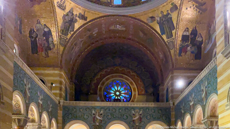 A blue circular window glows above a gallery framed by mosaics and arches.