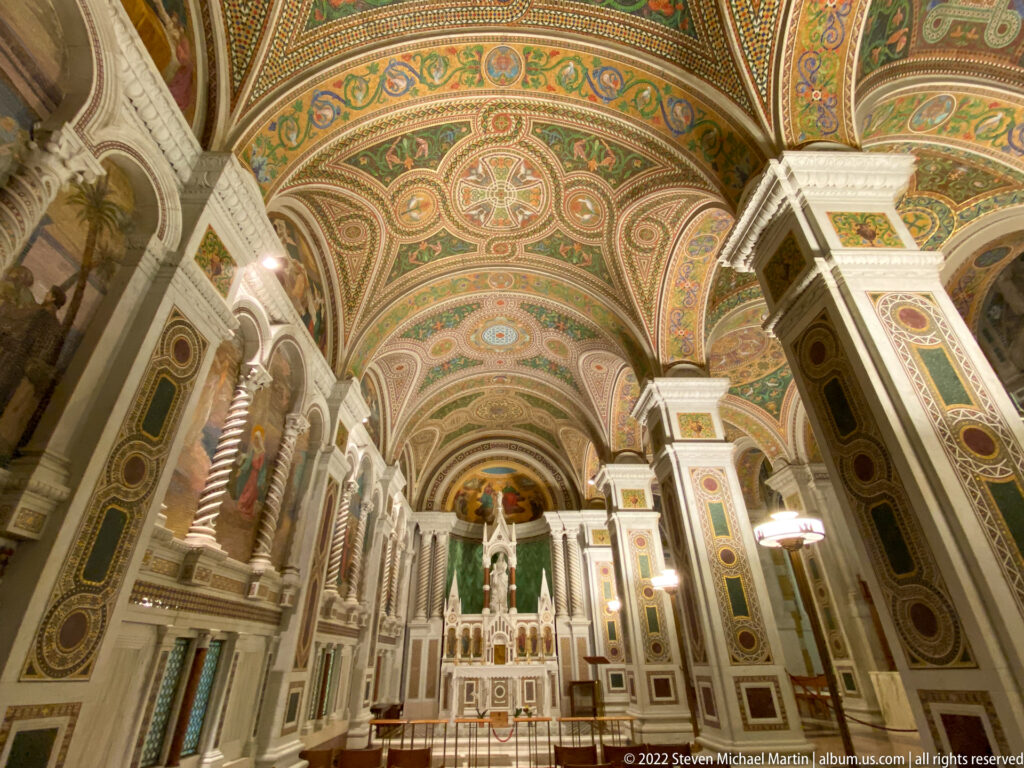 Ornamented columns and mosaic vaults frame the altar in an angled cathedral interior view.