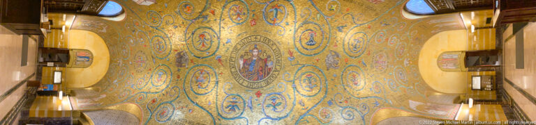 A long gold mosaic vault with circular motifs and a central medallion spans the cathedral hall.