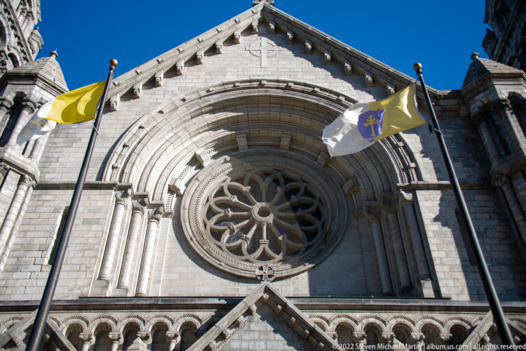 Two flags hang beside the cathedral’s rose window above the arched entrance.