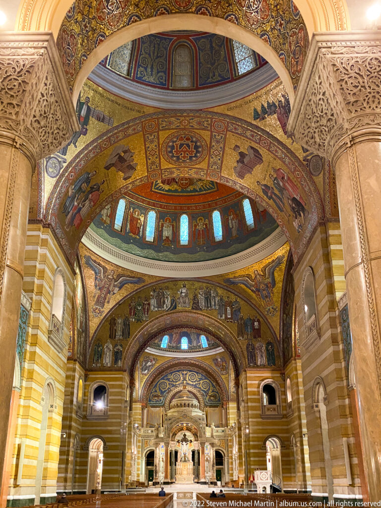An upward view follows mosaic-covered arches and vaults toward the cathedral sanctuary.