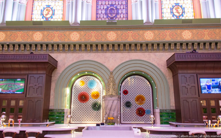 Three arched doorways sit beneath colorful patterned panels and an ornamental frieze.