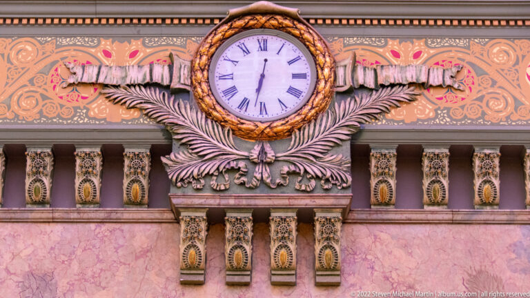 A Roman-numeral clock sits in a carved frame above a large foliate bracket.
