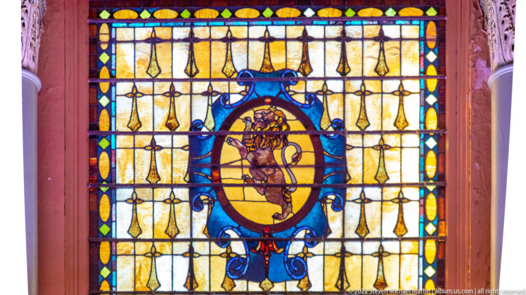 A stained-glass panel has a central blue oval motif surrounded by amber and yellow panes.