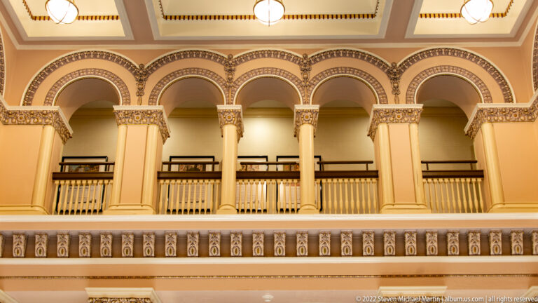 Five rounded arches and decorated columns line an upper gallery beneath a patterned ceiling in Union Station.