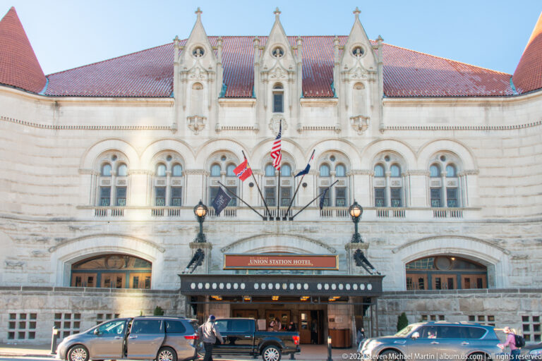 The Union Station Hotel façade has arched windows, roof gables, flags, and a busy entrance.