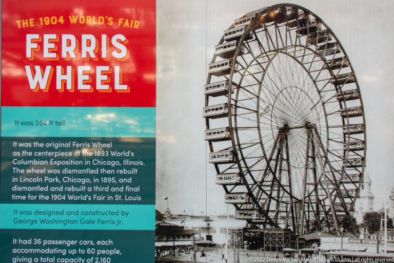 A black-and-white Ferris wheel image stands beside a red and turquoise interpretive panel.