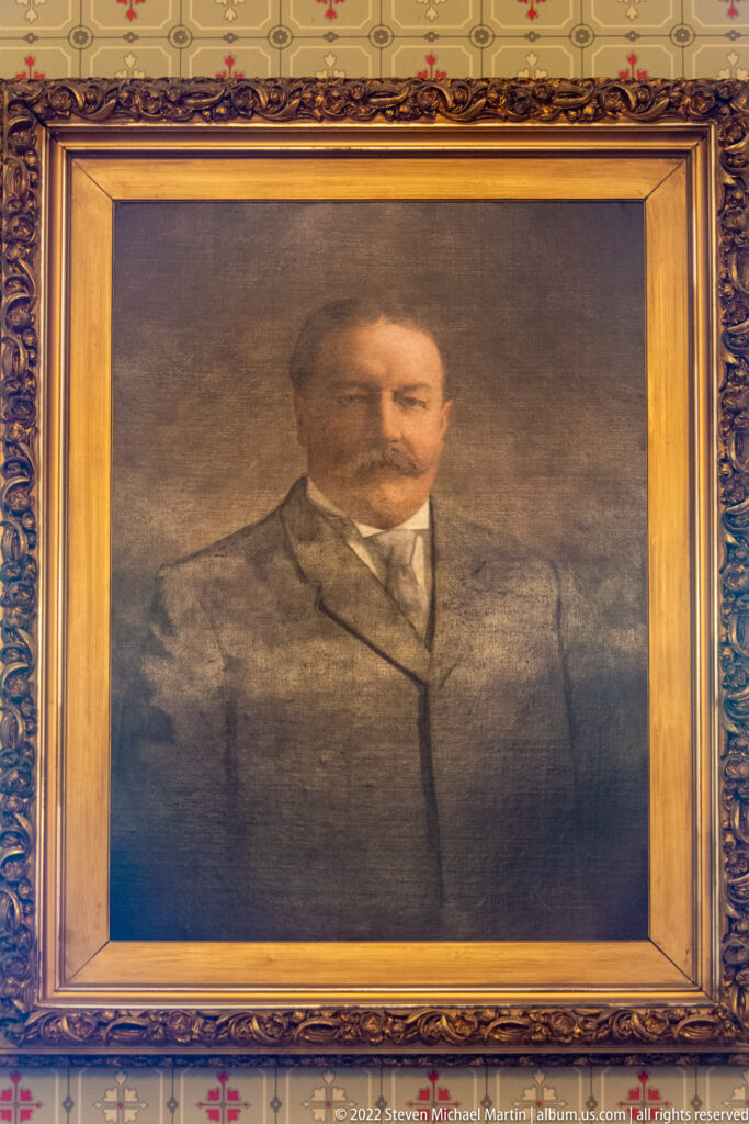 A large framed painting of William Howard Taft hangs above a carved fireplace.