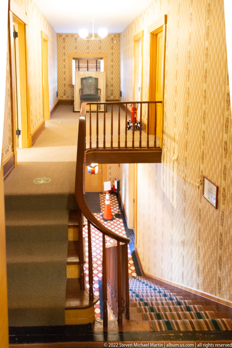 A curved wood railing surrounds an upper landing above the lower stair hall.