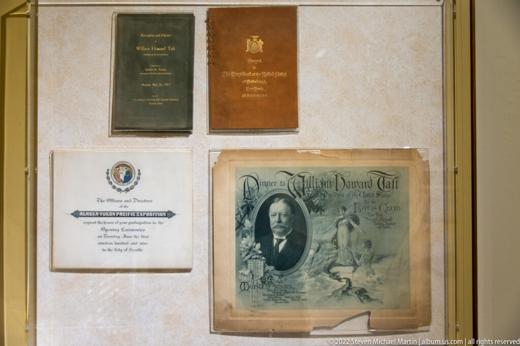 Several framed certificates and a portrait-bearing diploma are displayed together behind glass.