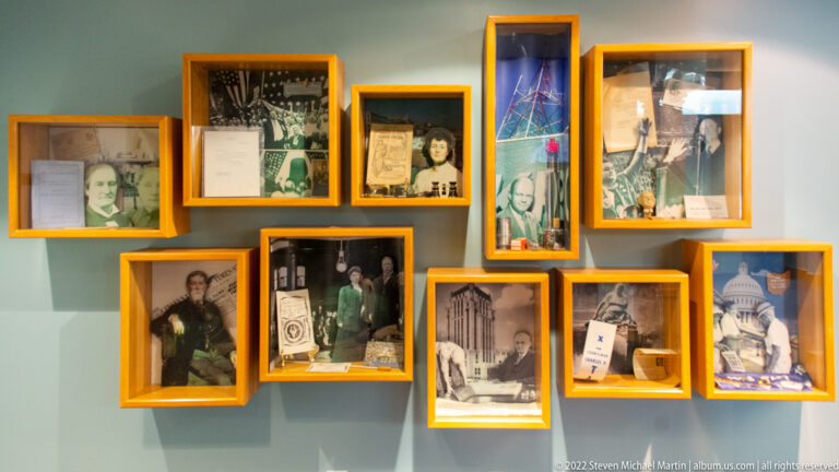 Yellow frames of varied sizes display family portraits, group photographs, a building image, and documents.