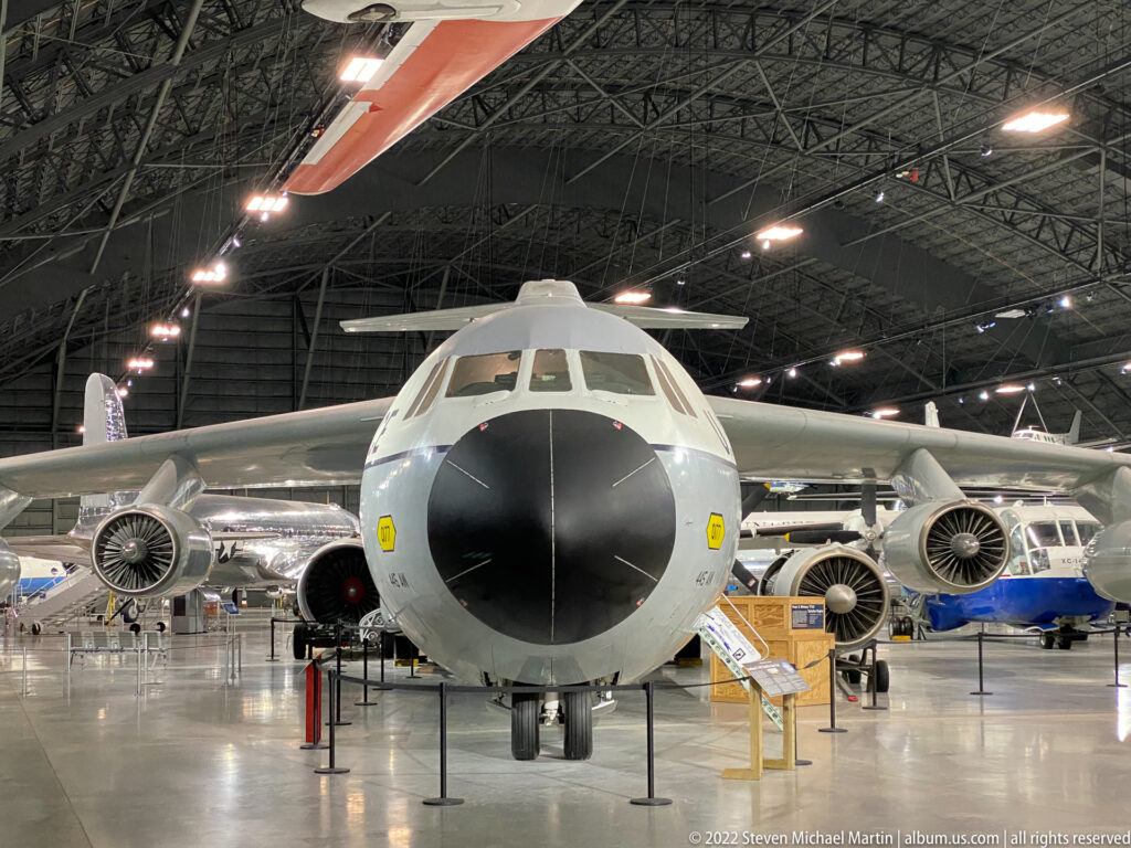 A large four-engine aircraft faces forward with its wings and engine nacelles spread across the hangar.