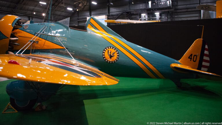 A turquoise aircraft marked with yellow stripes and the number 40 stands behind a yellow airplane wing.