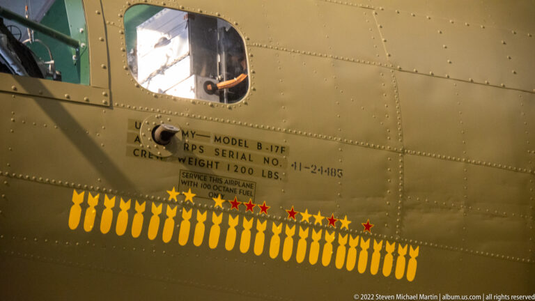 Bomb symbols and red stars form a mission tally beneath a B-17F stencil on an olive-drab fuselage.