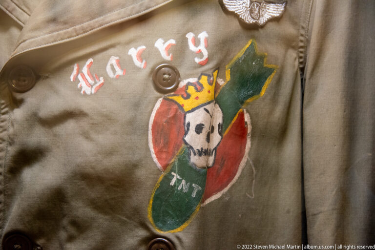 A hand-painted skull and red, green, and yellow motif decorate the front of a khaki flight jacket.