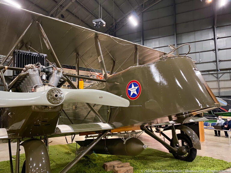 An olive military aircraft shows a radial engine, propeller, landing gear, and circular U.S. insignia.