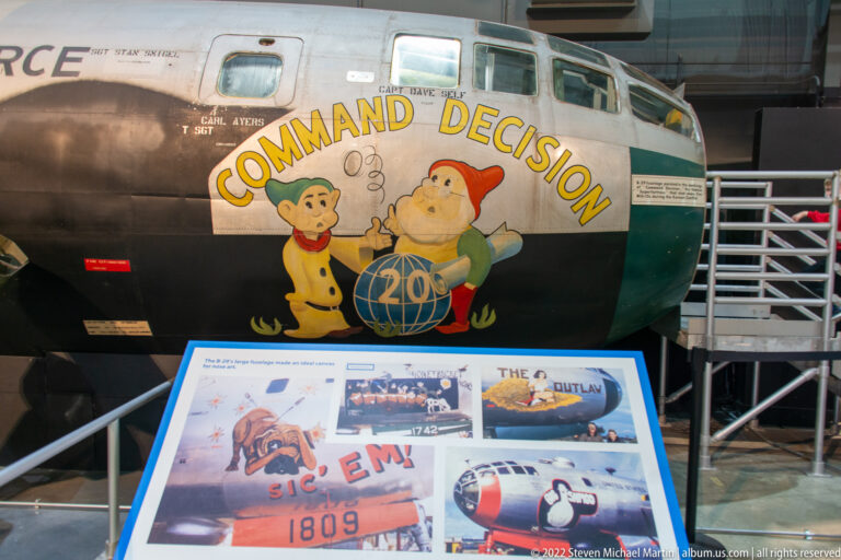 “Command Decision” nose art, two cartoon figures, and a painted globe decorate a bomber fuselage.