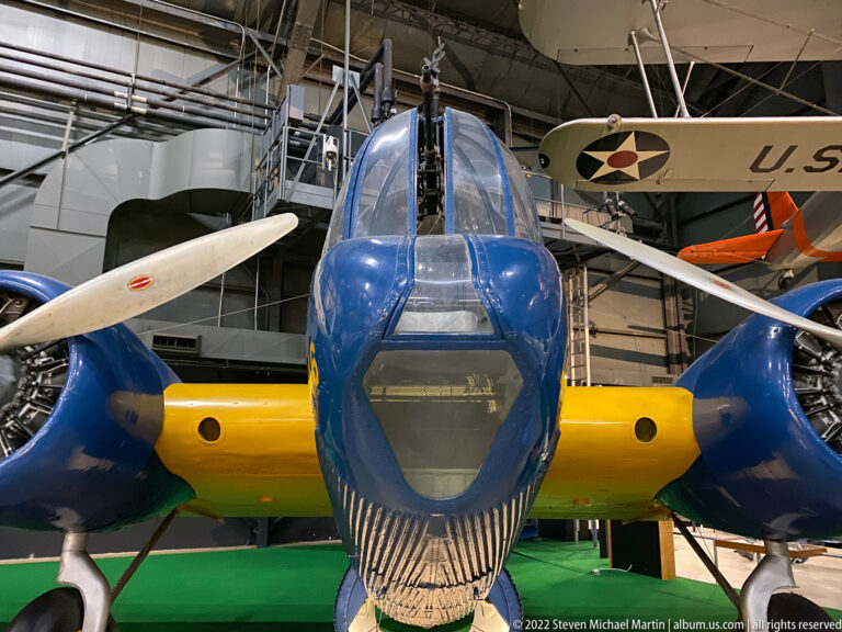 A blue aircraft with a yellow nose band faces the viewer, its cockpit framed by neighboring planes.