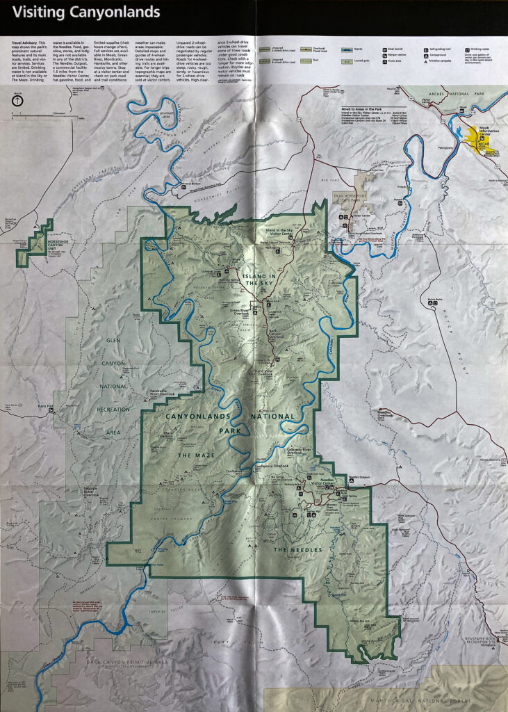 A folded park map marks a broad green boundary, blue waterways, roads, and surrounding terrain.