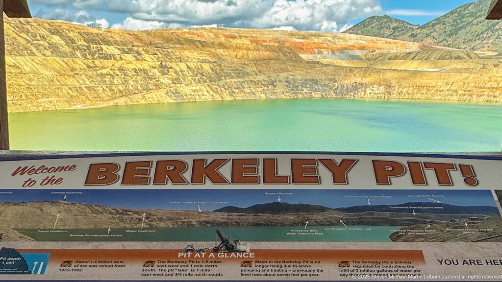 Green Berkeley Pit and terraced walls above a large Welcome to the Berkeley Pit interpretive panorama.