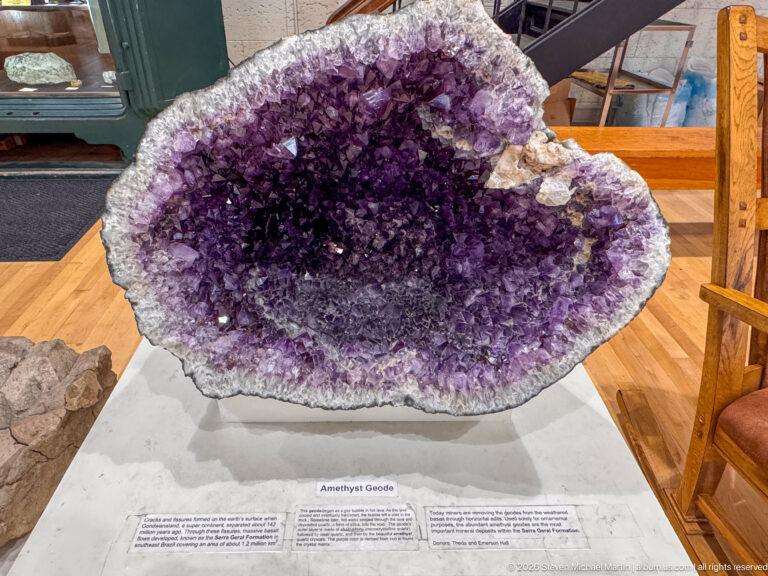 Large open geode densely lined with purple amethyst crystals and a pale crystalline rim.