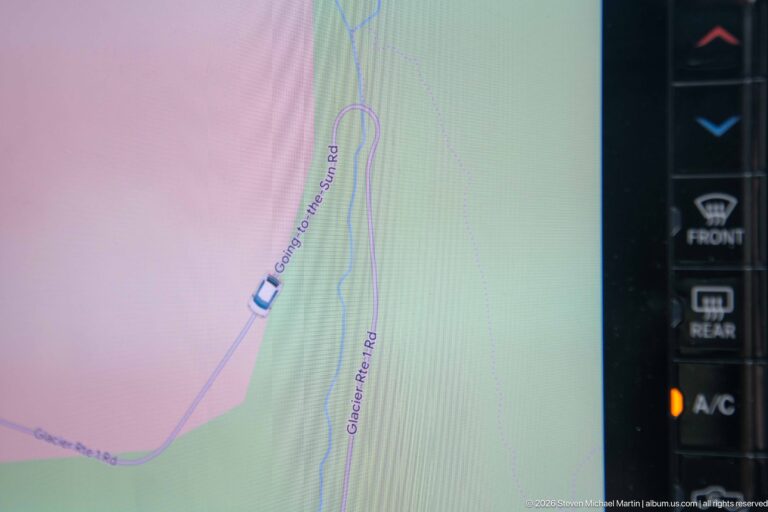 Vehicle navigation screen shows the car on Going-to-the-Sun Road beside Glacier Route Road.