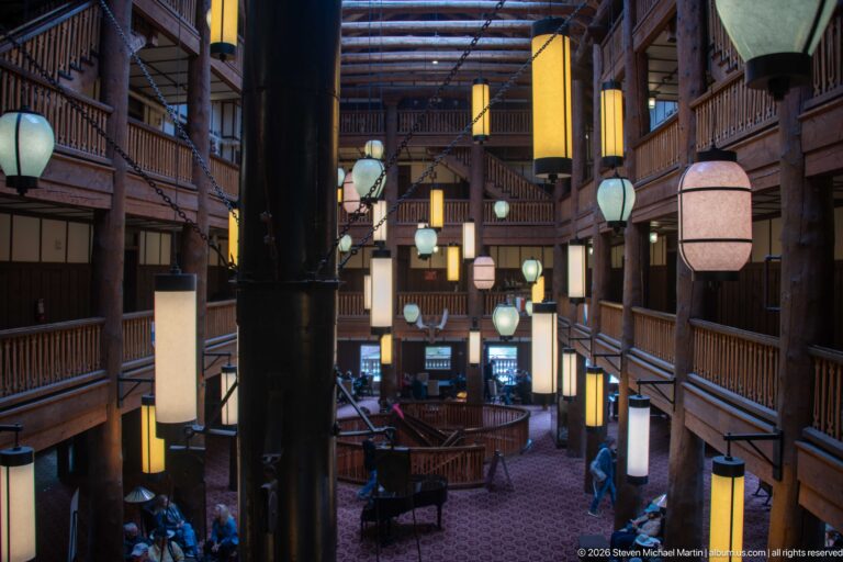 Black vertical chimney element amid hanging lanterns and stacked wooden balconies in the Great Room.