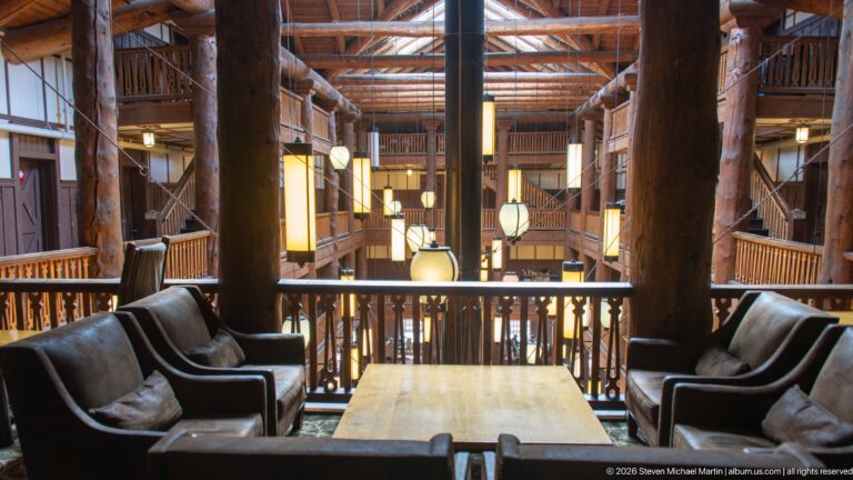 Leather armchairs around a wooden table on an upper balcony overlooking the lantern-filled Great Room.