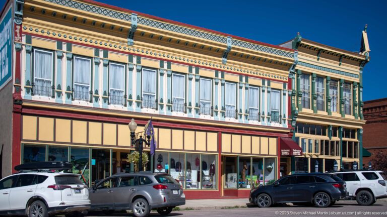 Long ornate Walker Commercial Company building with tall upper windows, decorative painted cornice, storefronts, streetlamps, and parked cars.