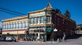 Corner view of the ornate Walker Commercial Company building with tall windows, decorative cornice, modern storefronts, and outdoor seating.