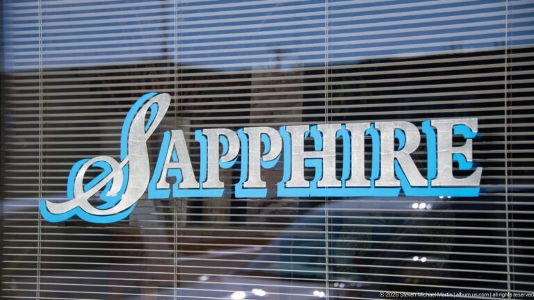 Blue-and-silver SAPPHIRE lettering across a storefront window backed by horizontal blinds.