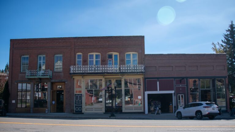 Historic Weinstein Building with paired upper windows and iron balcony beside an adjoining one-story storefront.