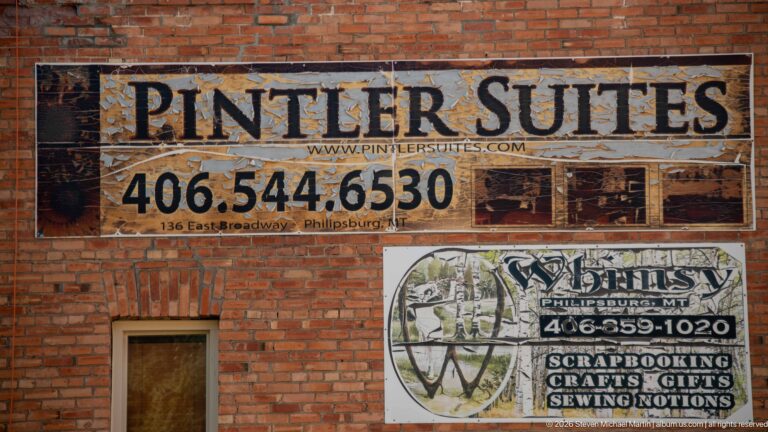 Weathered brick wall with large Pinter Suites advertisement and smaller Whimsy craft and gift shop sign.