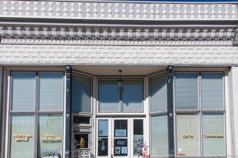 White historic storefront with red and dark decorative motifs, balustraded parapet, tall windows, and gold lettering for Montana-made artisan goods.