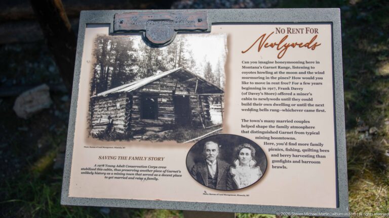 Interpretive panel titled No Rent For Newlyweds with a historic log cabin photograph and inset portrait of a couple.