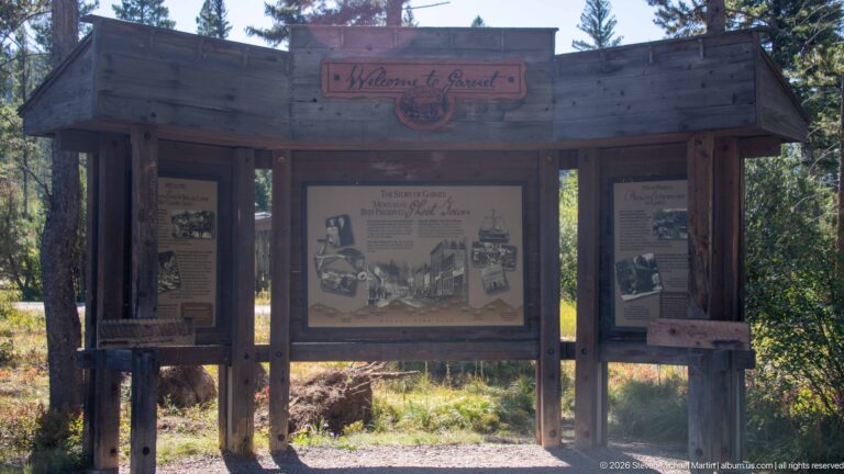 Timber outdoor kiosk with carved Welcome to Garnet header and three large interpretive panels set among trees.