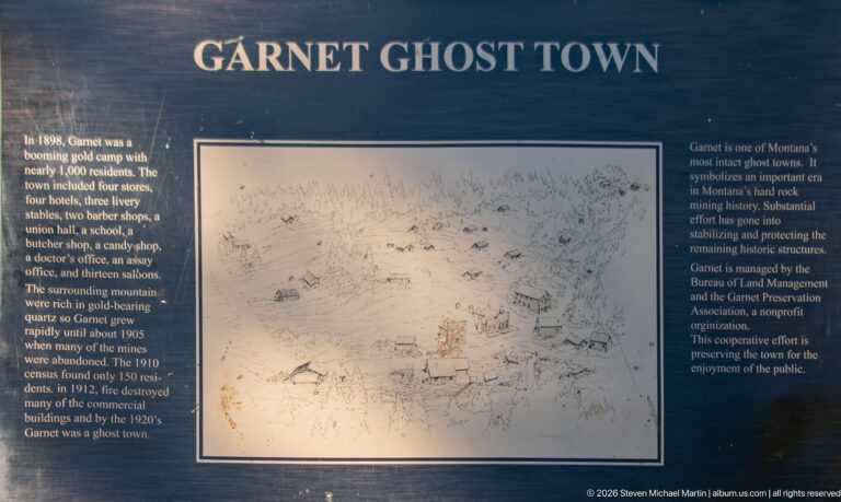Garnet Ghost Town interpretive panel with historical text surrounding a hand-drawn overview of the former mining settlement.