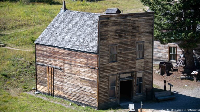 Two-story weathered wooden false-front building with paired upper windows and recessed ground-floor entrance at Garnet Ghost Town.