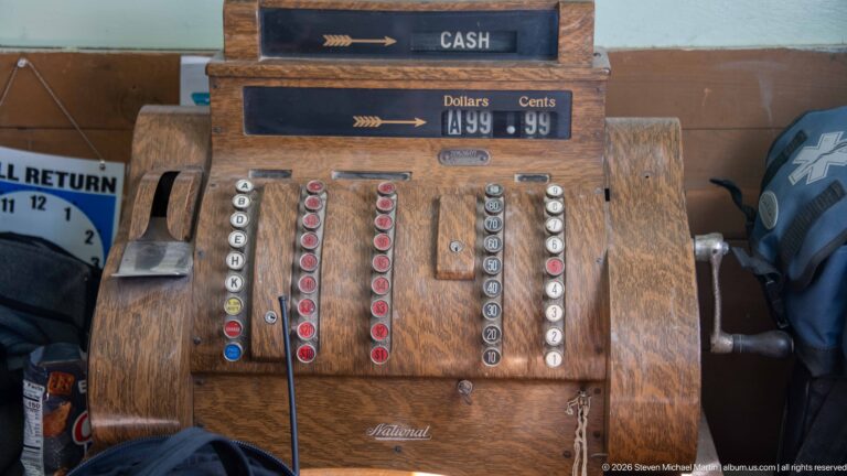 Wood-cased National mechanical cash register with rows of colored keys, numbered buttons, side crank, and raised cash display.